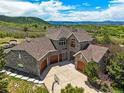 Aerial view of a stone house featuring a three-car garage and a basketball hoop in the driveway at 4222 Serenade Rd, Castle Rock, CO 80104