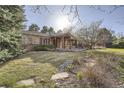 Home featuring a covered front porch, stone walkway, and lush landscaping at 4401 Sombrero Cir, Littleton, CO 80123