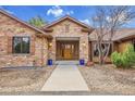 Welcoming front entrance with stone accents, a wooden door, and manicured landscaping create great curb appeal at 4700 Homestead St, Bow Mar, CO 80123