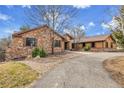 Charming exterior of home featuring a combination of stone and wood, complemented by a winding driveway and mature trees at 4700 Homestead St, Bow Mar, CO 80123