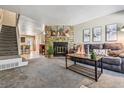 Cozy living room featuring a stone fireplace, plush sofa, and staircase access at 12059 E Hoye Dr, Aurora, CO 80012