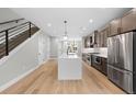 Open-concept kitchen with island, stainless steel appliances, wood floors, and view of the staircase at 1306 Yates St, Denver, CO 80204