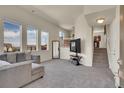 Cozy living room with plush carpeting, large windows, and neutral-toned sectional sofa at 1651 Aspen Meadows Cir, Denver, CO 80260