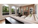 Bright living room with large arched windows, brick fireplace, built-in shelving, and comfortable seating at 11056 W Rowland Ave, Littleton, CO 80127