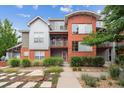 Contemporary two-story brick townhome with metal accents, landscaped yard, and walkway at 85 Uinta Way # 405, Denver, CO 80230