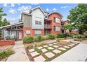 Charming brick and metal townhouse with landscaped yard, walkway, and small patio area at 85 Uinta Way # 405, Denver, CO 80230