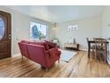 Inviting living room with hardwood floors, a cozy red sofa, and a large window offering natural light at 3341 Oneida St, Denver, CO 80207