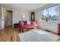 Bright living room featuring hardwood floors, a comfortable red sofa, and large windows at 3341 Oneida St, Denver, CO 80207