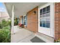 Covered front porch with a seating area, brick accents, and a clear view through the front door at 3308 W 11Th Avenue Pl, Broomfield, CO 80020