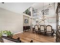 Elegant dining area with a grand chandelier, wood floors, staircase, and views of the upper level at 9407 W Gibraltar Pl, Littleton, CO 80127
