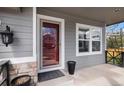 Inviting covered porch with a stylish red door, neutral siding, and classic exterior lighting fixture at 9407 W Gibraltar Pl, Littleton, CO 80127