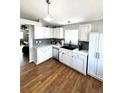 Updated kitchen featuring white cabinets, stainless appliances, a black sink, and hardwood floors at 5343 S Ukraine Way, Aurora, CO 80015