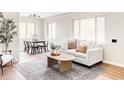 Bright living area showcasing a modern sofa, stylish rug, and light-filled dining area at 2340 Jamaica St, Aurora, CO 80010