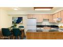 Cozy kitchen and dining area featuring a sleek black countertop, white appliances, and ample cabinet space at 5995 W Hampden Ave # 3E, Denver, CO 80227