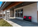 Cozy covered front porch furnished with a dark bench and red pillows at 745 S Eliot St, Denver, CO 80219