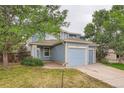 Two-story home features blue siding, beige trim, dual garages, and landscaping at 897 Mockingbird Ln, Brighton, CO 80601