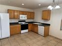 Functional kitchen with wooden cabinets, standard appliances, and tile flooring, perfect for culinary endeavors at 897 Mockingbird Ln, Brighton, CO 80601