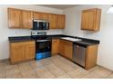 Bright kitchen featuring wood cabinets, stainless steel appliances, and tile flooring at 897 Mockingbird Ln, Brighton, CO 80601