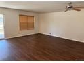Spacious living room with hardwood floors, ceiling fan and large window providing natural light at 897 Mockingbird Ln, Brighton, CO 80601