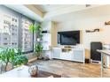 Sunlit living room featuring a large window with a city view, a TV and modern shelves with decorations and plants at 1750 Wewatta St # 705, Denver, CO 80202