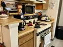 A kitchen featuring white appliances, wood cabinets and a variety of cookware on the stovetop at 14172 E Colorado Dr # 204, Aurora, CO 80012