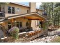 An outdoor covered patio features stone accents, wood ceilings, and comfortable seating for entertaining at 17015 Oxbridge Rd, Monument, CO 80132