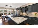 Modern kitchen boasting granite countertops, dark cabinetry, stainless steel appliances, and access to the outdoor patio at 17015 Oxbridge Rd, Monument, CO 80132