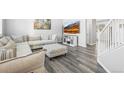 Cozy living room featuring a plush sectional, modern entertainment center, light gray walls and gray plank flooring at 26890 E Roxbury Pl, Aurora, CO 80016