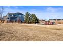 Blue two-story home with a playground in a well-maintained grassy area with a clear blue sky at 21093 E Hampden Pl, Aurora, CO 80013