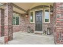 Inviting front porch with brick columns, stylish lanterns, and a welcoming entrance at 7400 S Genoa Cir, Centennial, CO 80016