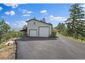 Two-car garage with living space above, and a paved driveway on a sunny day at 8045 Eagle Rd, Larkspur, CO 80118