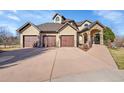 Elegant home with a three-car garage, stone entryway, and landscaped front yard on a sunny day at 4337 W Hinsdale Ave, Littleton, CO 80128