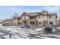 Multi-story condo with stone accents and covered parking in a snowy setting at 10437 W Hampden Ave # 104, Lakewood, CO 80227