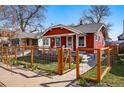 Charming red house featuring a fenced front yard with new plantings, sidewalk, and inviting curb appeal at 4452 Zenobia St, Denver, CO 80212