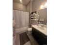 Neutral bathroom with a shower/tub combo, white shower curtain, floating shelves, and a dark vanity at 7790 S Queensburg Way, Aurora, CO 80016