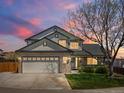 Charming two-story home with a brick facade, a well-manicured lawn, and a spacious two car garage at dusk at 13972 Hudson Way, Thornton, CO 80602
