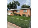 Ranch style brick home with a neatly kept lawn and chain link fence at 3515 Pierce St, Wheat Ridge, CO 80033