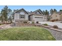 Beautiful home featuring stone accents, manicured lawn, and a three-car garage at 1798 Summerglow Ln, Monument, CO 80132