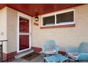 Inviting front porch with seating area and a stylish red door with a 'Welcome' mat at 3559 Hudson St, Denver, CO 80207
