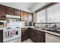 Well-lit kitchen with wooden cabinetry, a double sink, and white appliances at 2567 Rainbow Dr # 80, Denver, CO 80229