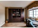The office features custom built-in wooden bookshelves, laminate flooring and a large bright window at 13871 Ivy St, Thornton, CO 80602