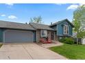 Charming exterior with blue siding, stone accents, well-manicured lawn, and two red Adirondack chairs at 21524 E Powers Pl, Centennial, CO 80015