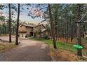 Charming home nestled among mature trees, featuring a stone-accented exterior and a long private drive at 17540 Caribou Dr, Monument, CO 80132