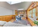 Cozy living room featuring a stone fireplace, skylights, and wood-paneled walls at 879 S Cole Dr, Lakewood, CO 80228