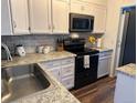 Modern kitchen featuring stainless steel appliances, white cabinetry, and sleek countertops at 15507 E Louisiana Ave, Aurora, CO 80017
