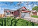 Charming brick-and-red-sided home with a well-maintained lawn, mature tree, and attached two-car garage at 7598 Jared Way, Littleton, CO 80125