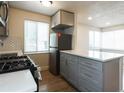 Close-up of an updated kitchen with gray cabinets, stainless steel appliances, and wood flooring at 1564 Verbena St, Denver, CO 80220