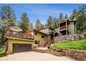 Charming home featuring a multi-level deck, natural stone accents, and lush landscaping at 25808 Sunrise Ln, Golden, CO 80401