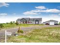 Inviting gray home with red accents, featuring a well-manicured lawn and a detached garage, perfect for country living at 196 W 8Th Ave, Byers, CO 80103