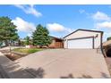 Large concrete driveway leads to a detached two-car garage with a white door at 10949 E 109Th Pl, Northglenn, CO 80233
